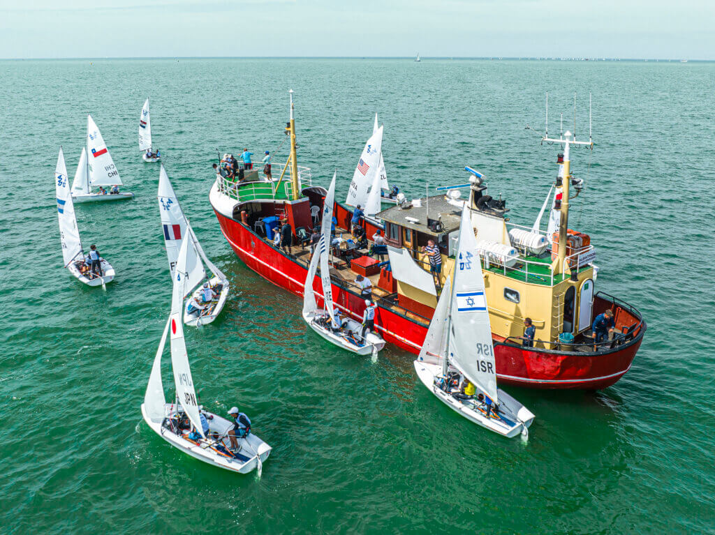 De coaches verblijven tijdens de wedstrijden op dit WK Jeugdzeilen op een vissersboot om het gebruiks van RIBs te verminderen